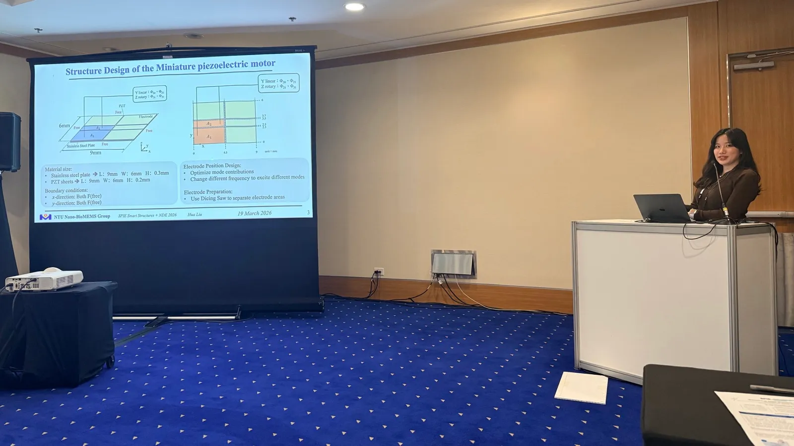 Flora Liu at the lectern at SPIE Smart Structures + NDE 2026, beside a slide titled "Structure Design of the Miniature piezoelectric motor".